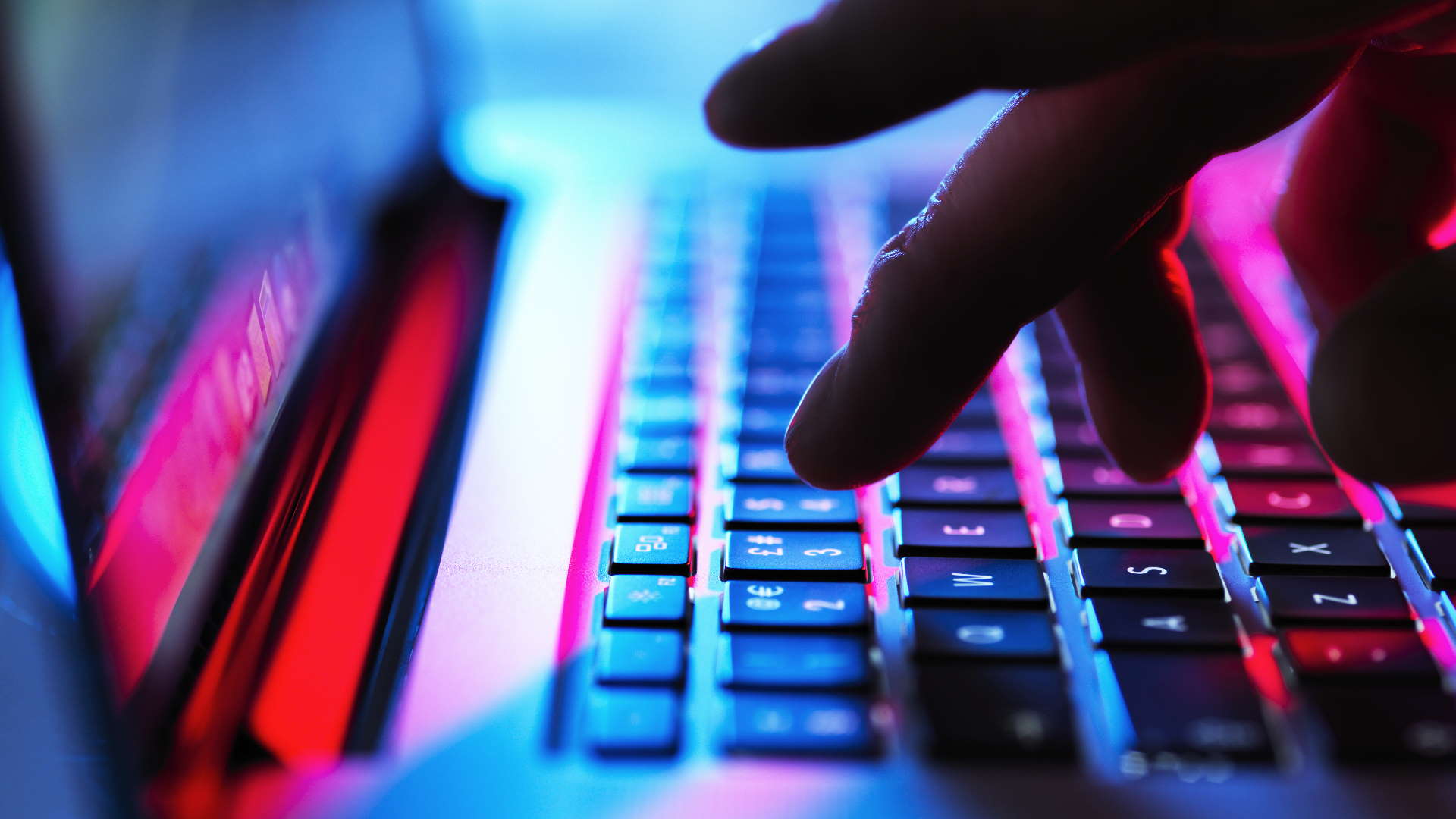 Person typing on a laptop with red and blue lighting